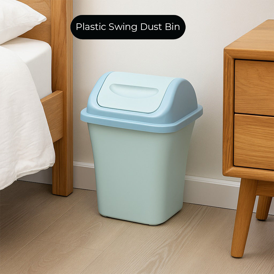 Light blue plastic swing dust bin in a bedroom setting with wooden furniture.