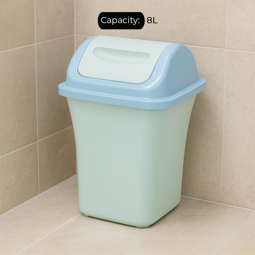 Small green trash bin with a blue lid on a tiled floor.